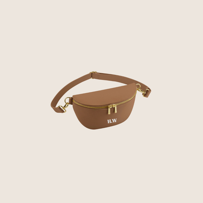 Brown waist/belt bag with gold accents on a beige background