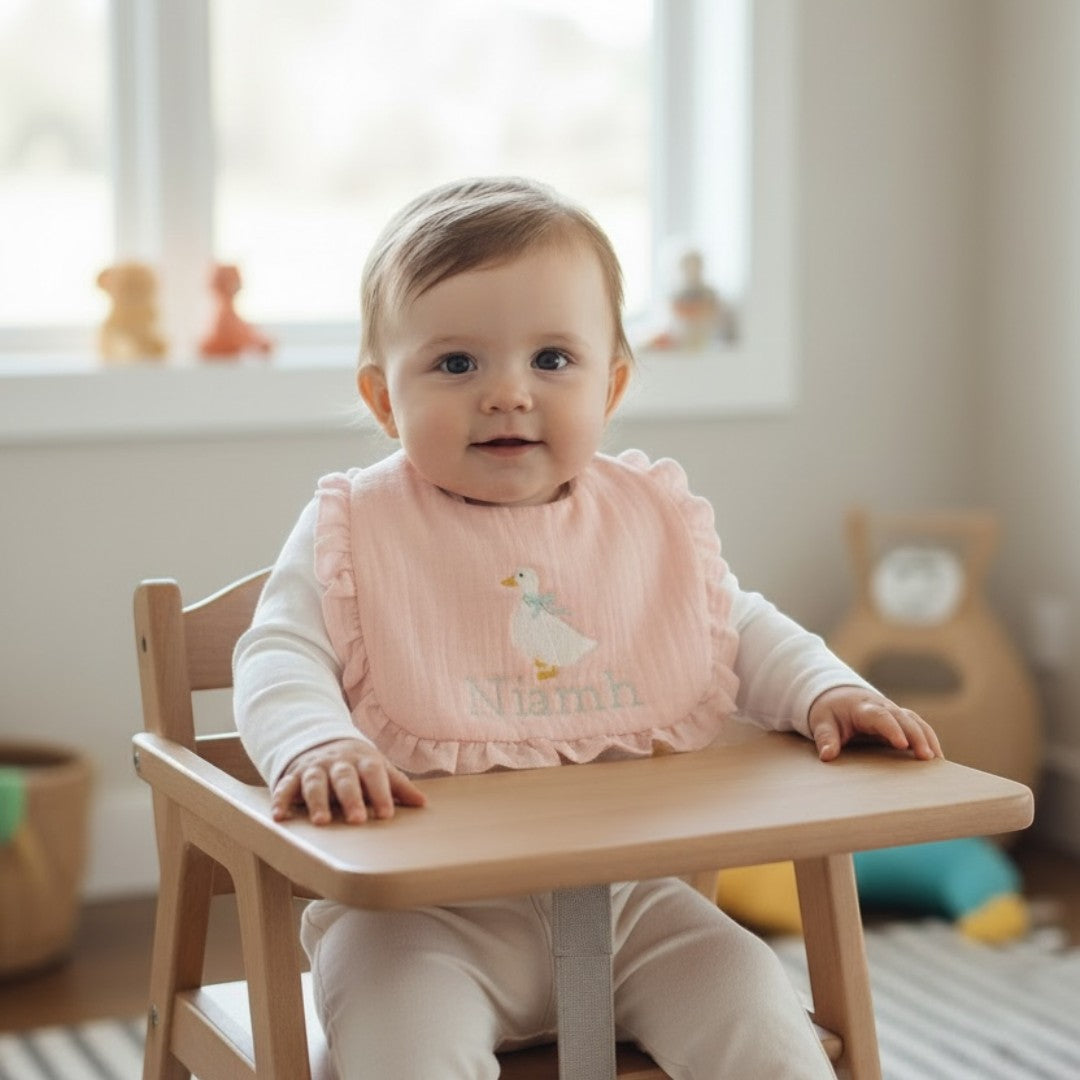 The Wee Rhubarb Gift Co Ltd light pink muslin baby bib with embroidered goose and ruffles. Features name 'Niamh'.