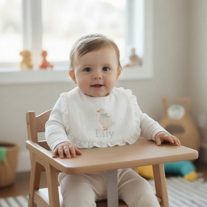 The Wee Rhubarb Gift Co Ltd white muslin baby bib with embroidered duck, mint bow, ruffles, and name 'Lily'.